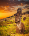 Каменна статуя Моай на Великденския остров (Rapa Nui), Чили, заснета по време на драматичен залез сред зелени хълмове.