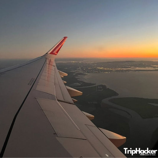 Гледка от самолетно крило по време на полет по залез над крайбрежие - идея за пътуване, планиране на ваканция и консултации за пътувания